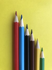 Close-up of colored pencils against yellow background