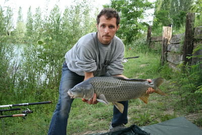 Side view of a man holding fish in field