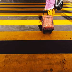 Low section of woman with luggage walking on road