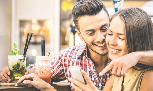 Happy tourist couple using smart phone at outdoor restaurant