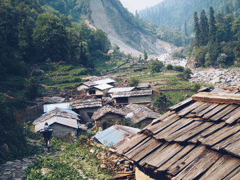 Rear view of man walking by houses against mountains