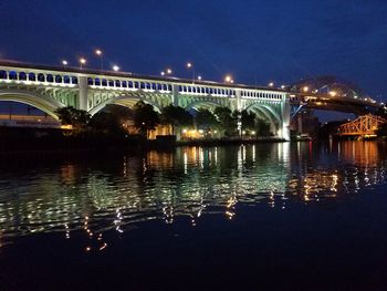 Illuminated bridge over river against sky at night