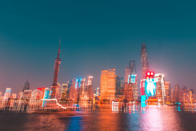 Illuminated buildings in city against sky