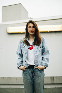 Portrait of young woman standing against wall