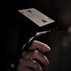 Cropped hand playing cards in darkroom