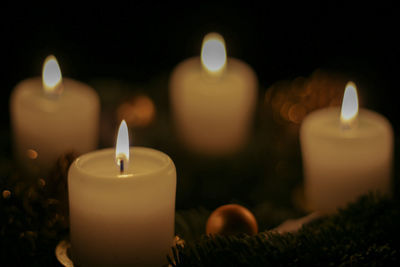 Close-up of lit candles in darkroom