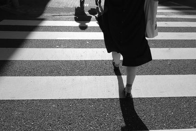 Low section of woman walking on zebra crossing