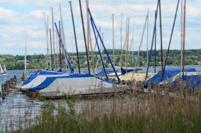 Boats moored on grass against sky