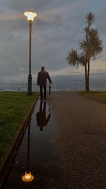 Man with umbrella on street against sky