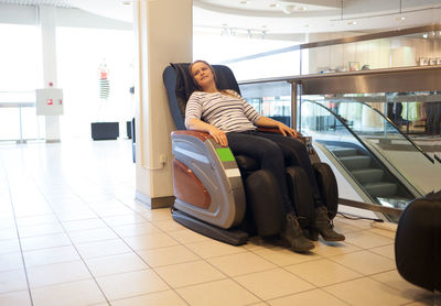 Woman sitting on massage chair at shopping mall