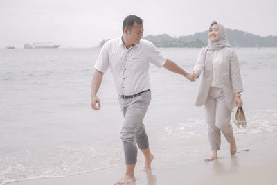Full length of friends standing on beach