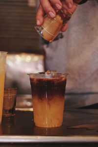 Midsection of person pouring drink in glass