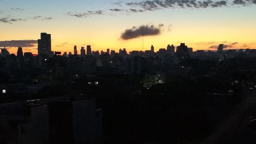 Silhouette buildings in city during sunset