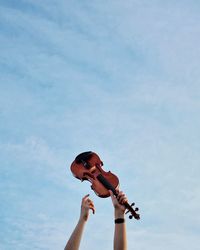 Low angle view of man playing guitar against sky