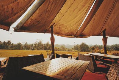 Empty chairs and tables at restaurant against sky