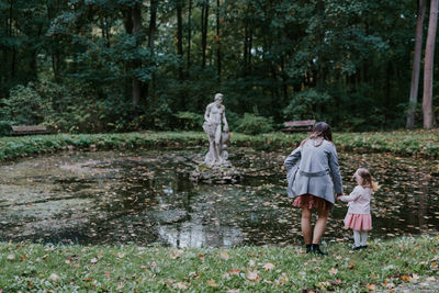 Rear view of women standing by plants against trees