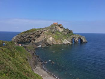 Scenic view of sea by cliff against blue sky