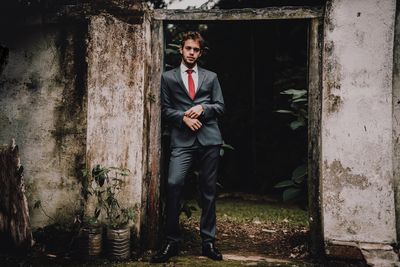 Portrait of young man standing against wall