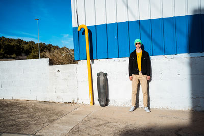 Portrait of young man standing against wall