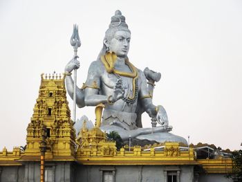 Low angle view of statue against building against clear sky