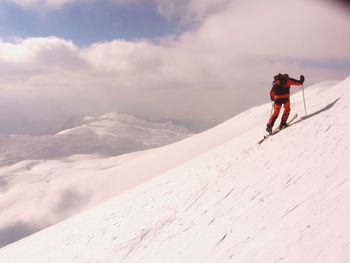 Rear view of man and woman on mountain against sky during winter