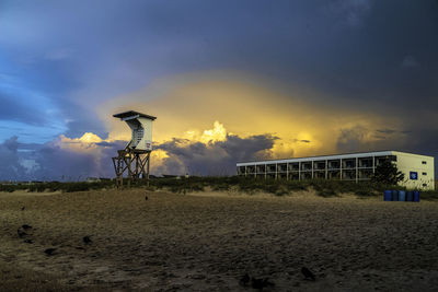 Lifeguard hut on beach against sky during sunset