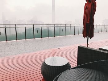 View of chair by railing against cityscape