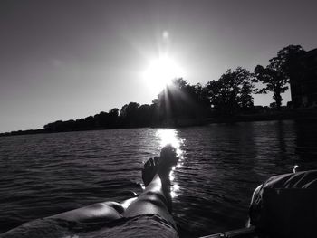 Low section of man relaxing in water at sunset