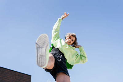 Low angle view of woman against blue sky