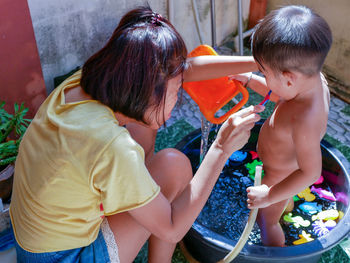 Mother brushing teeth of son in yard