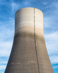 A huge chimney of a nuclear power plant close up on a background of blue sky with clouds.