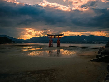 Scenic view of torii gate on beach against sky during sunset