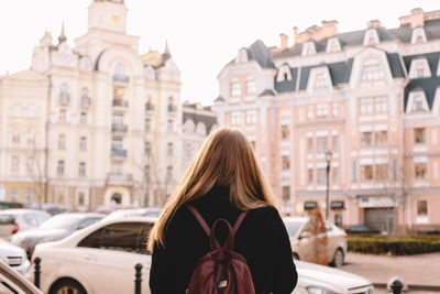 Rear view of woman with backpack standing on city street