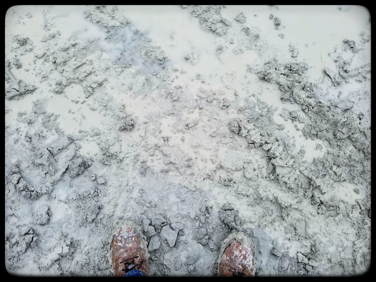 LOW SECTION OF PERSON STANDING ON SNOW COVERED LANDSCAPE