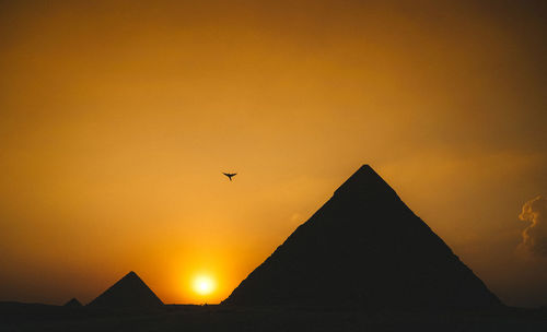 Low angle view of silhouette bird flying against sky during sunset