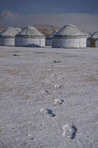 Built structure on field by snowcapped mountain against sky