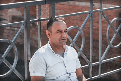 Portrait of man standing by fence