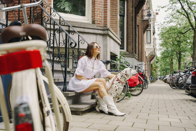 Rear view of woman with dog sitting on street