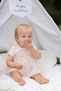 Portrait of cute baby girl sitting on bed