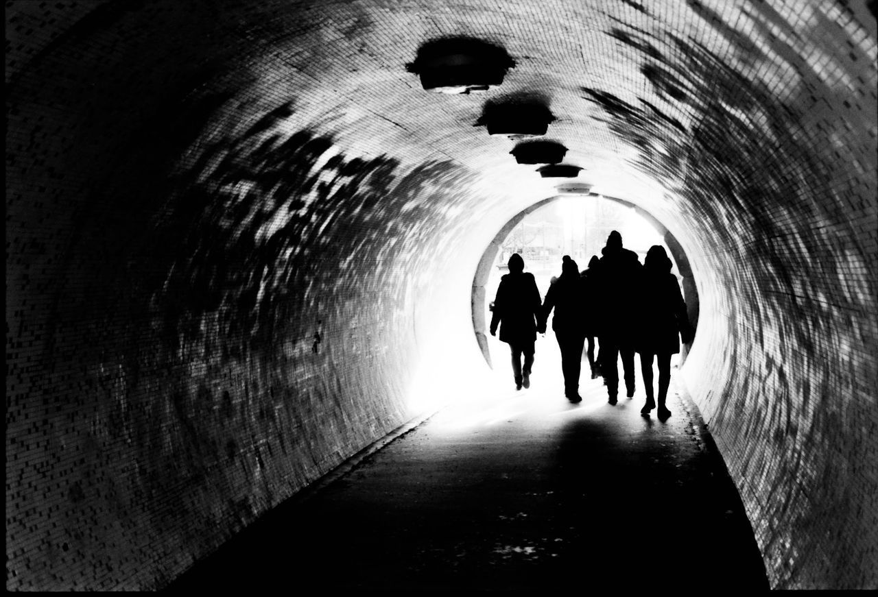 REAR VIEW OF PEOPLE WALKING IN TUNNEL