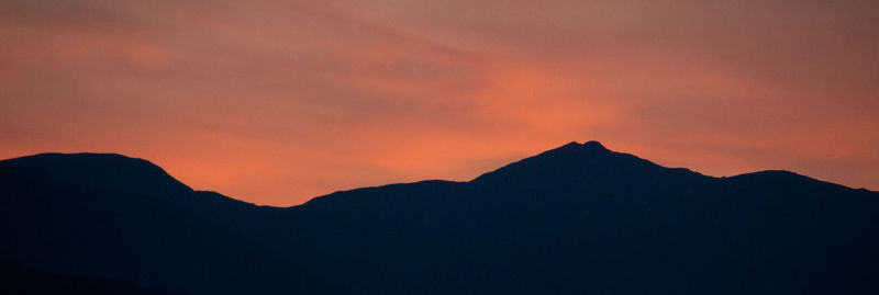 Scenic view of silhouette mountains against orange sky