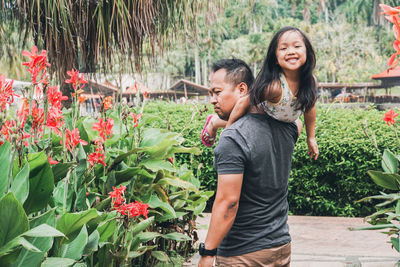 Father with daughter standing against plants