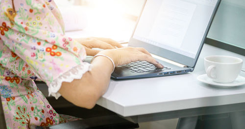 Midsection of woman using mobile phone while sitting on table