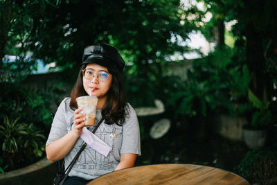 Portrait of young woman standing against trees