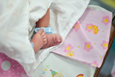 Low section of newborn baby resting on bed in hospital