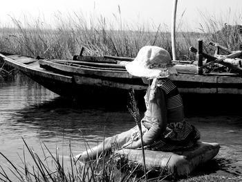 Rear view of woman sitting on boat moored at shore