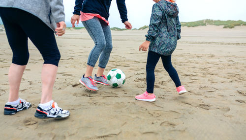 Woman with mother and daughter playing ball at beach