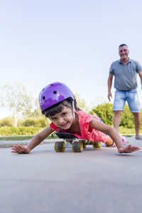 Girl playing with his father while roller skating outdoors in the park.