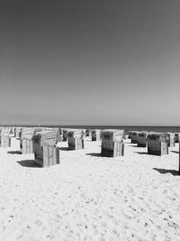 Hooded chairs on beach against clear sky