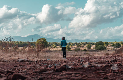 Rear view of man standing on field against sky